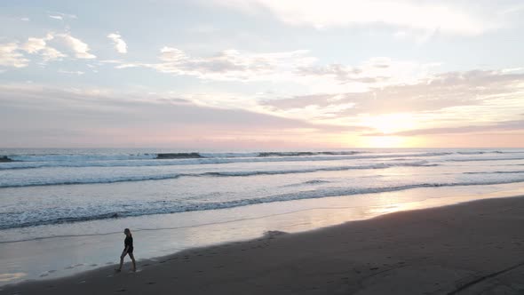 Young woman walking along a dream beach in the tropics at sunset then exiting the frame while many l