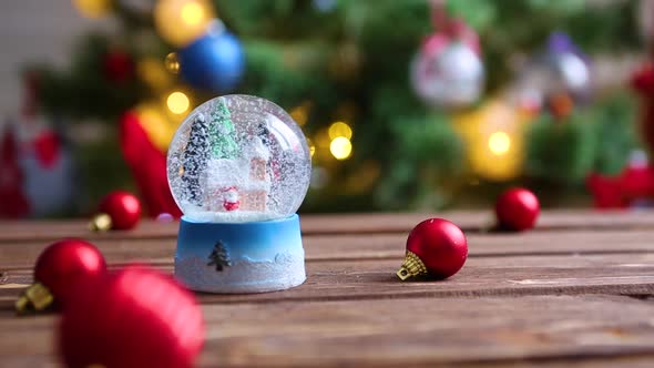 Christmas Snow Glass Ball on Background of Christmas Tree with Christmas Lights