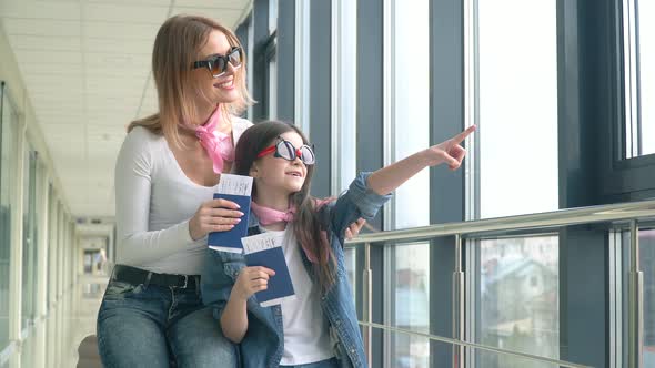 Female and Little Girl Holding Passports and Airline Boarding Pass Tickets