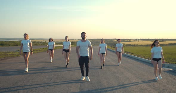 Big Group of People in White Shirts Are Walking on the Road Early in the Morning