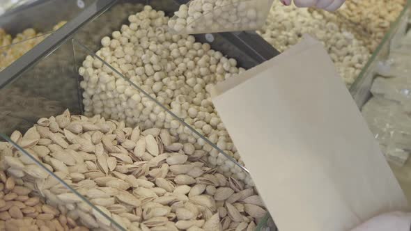 Female Caucasian Hand Picking Raw Organic Macadamia Into Paper Pack. Unknown Female Client Taking