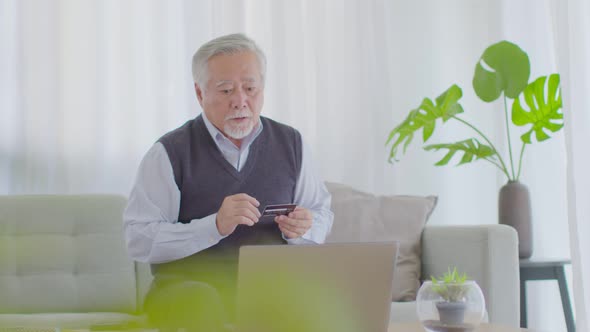 Problem of payment in elderly asian man using computer laptop and credit card to shopping online