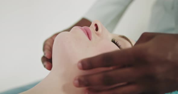 Young Beautiful Caucasian Woman Lying on Spa Bed Get Facial Massage Treatment