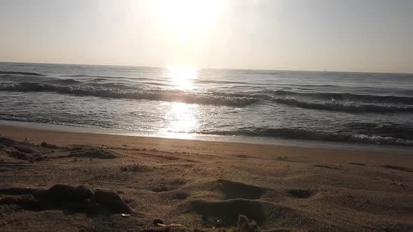 Beautiful sunset at the beach with waves slowly rolling on to the beach. Sunrise beach, ocean waves.