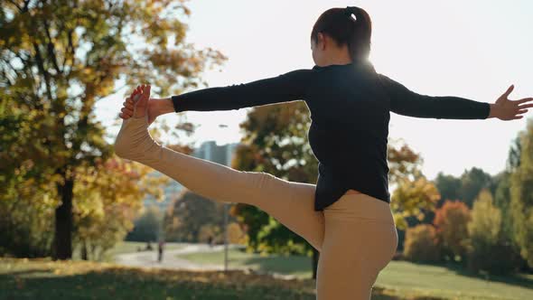 Girl Practices Extended Sideward Yoga Pose in Autumn City Park on a Yoga Mat