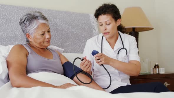 Female doctor measuring blood pressure of a senior woman 4k