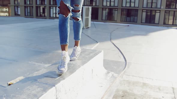 Legs of fashionable young woman walking on urban rooftop