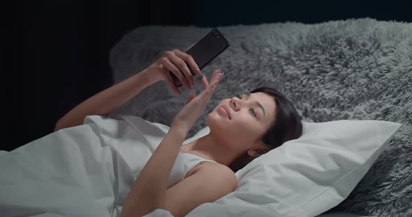 Woman Scrolling Smartphone in Bedroom