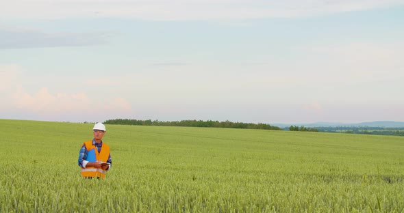 Engineer with Blueprint Analyzing Farm Against Sky