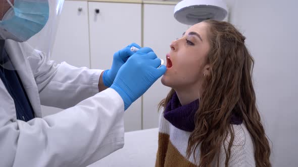 Male doctor examining throat of patient in clinic