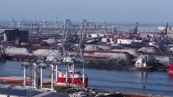 Industrial container cranes and anchored freight ship in Rotterdam port - aerial