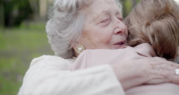 Grandmother Woman Kissing and Hugging Granddaughter at City Park