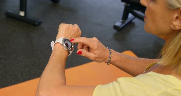 Senior woman checking her smartwatch in fitness studio 4k