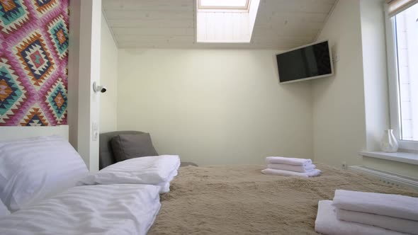 Interior of a spacious hotel bedroom on attic floor with fresh linen on a big double bed. Cozy 