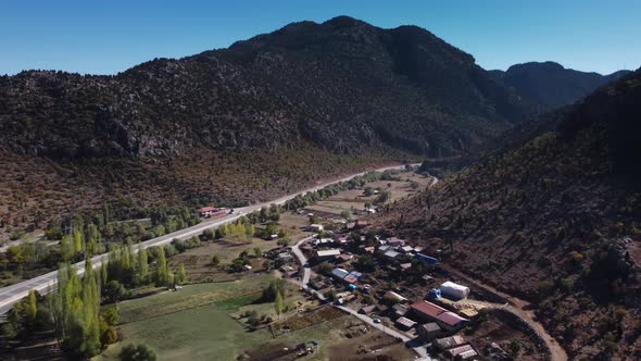 Landscape of Roadside Village Located on the Foot of Mountain in Turkey and Moving Cars on Highway