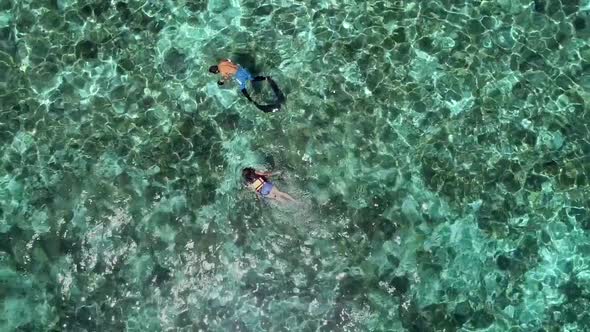 Aerial view of two people snorkeling with turtle in Panagsama Beach, Philippines.