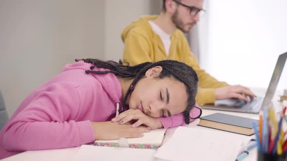 Young Caucasian Boy in Eyeglasses Waking Up Female African American Groupmate. Tired Student