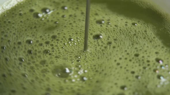 Whipping foam in a cup of traditional Japanese matcha green tea