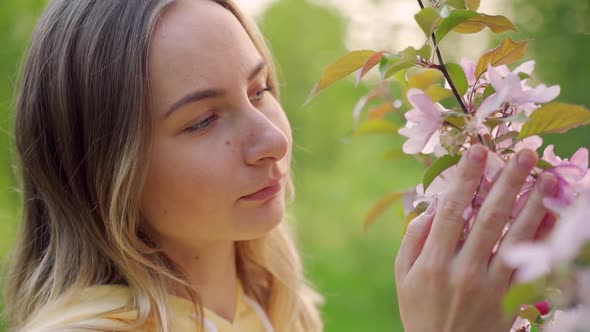 The Smell of Flowers in the Spring Garden. Attractive Girl Touches Flowers