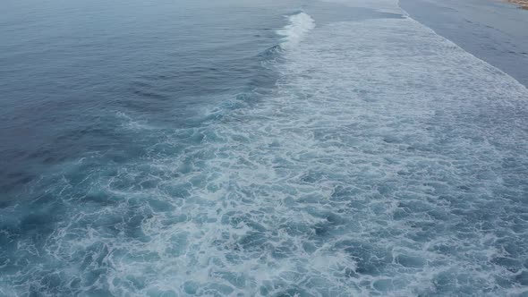 Aerial View of the Sea Smoothly Lapping Waves on a Cloudy Summer Day
