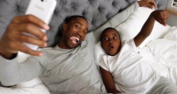 Father and son taking selfie with mobile phone in bedroom 4k