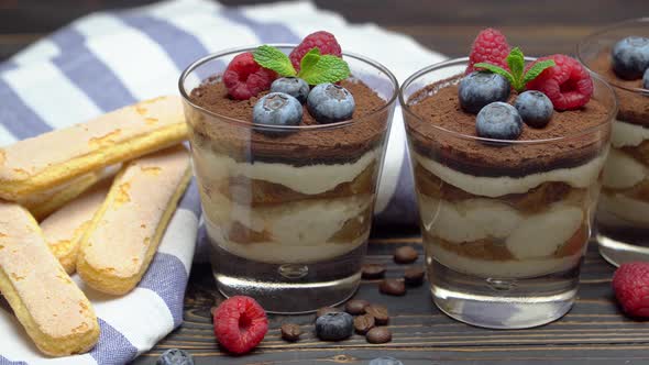 Classic Tiramisu Dessert with Blueberries and Strawberries in a Glass Cup and Savoiardi Cookies