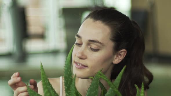 Young woman touching aloe vera plant and laughing cheerfully