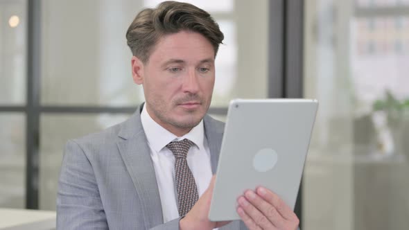 Attractive Middle Aged Man using Tablet in Office