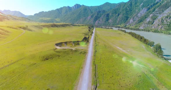 Aerial Rural Mountain Road and Meadow at Sunny Summer Morning. Asphalt Highway and River.