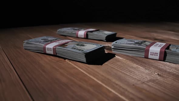 Three Stacks of 10000 American Dollars Banknotes in Bundles Lie on Wooden Table