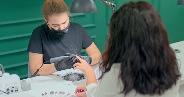 Professional Manicurist Removes Varnish From a Client’s Nails Using Special Equipment