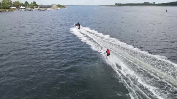 Closeup drone video of waterskiing on a fjord with landscape and marina as background