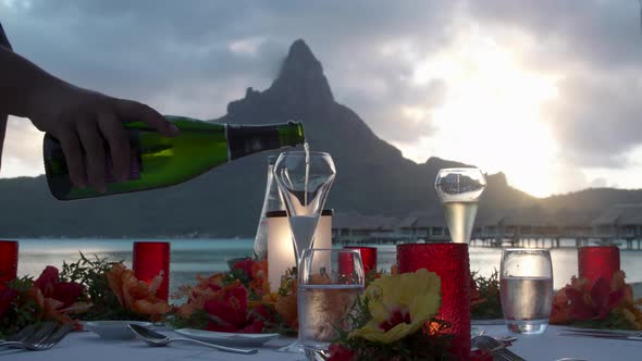 A man pouring champagne sparkling wine at a tropical island resort.