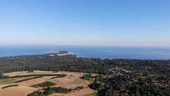 Aerial view of the coastline of Sejerøbugten with hills, fields and ocean.