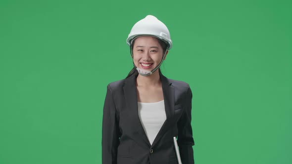 Smiling Asian Female Engineer With Safety Helmet Holding A Laptop In The Green Screen Studio