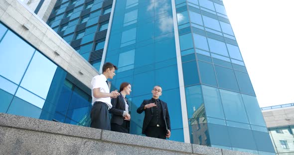 Group of Young People Standing Near Glass Building Business Center Skyscraper, Partners Discussing