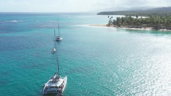 Luxurious boats anchored at Playa Punta Popy, Las Terrenas in Dominican Republic. Aerial backward