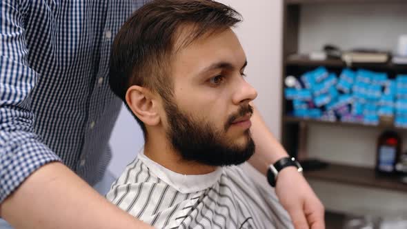 Barber Prepares the Client for a Haircut. Modern Small Business Concept. The Charismatic Young Man