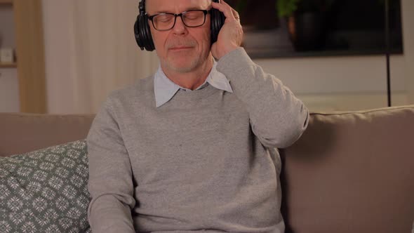 Old Man in Headphones Listening To Music at Home