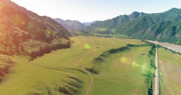 Aerial Rural Mountain Road and Meadow at Sunny Summer Morning. Asphalt Highway and River.