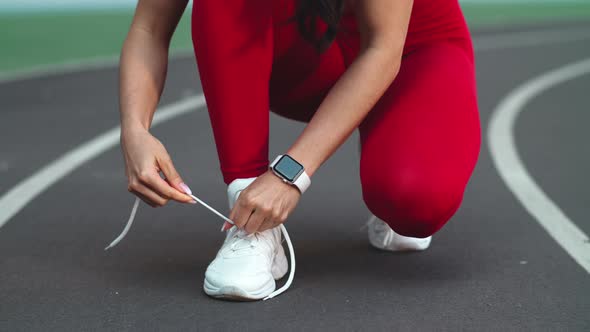 Close Up of Fitness Woman Lacing Up Footwear for Marathon on Track