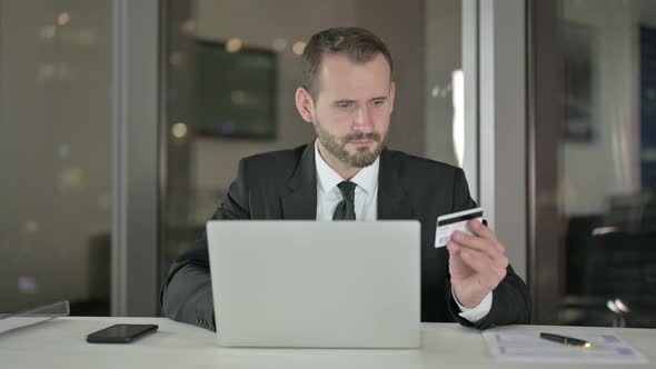 Handsome Businessman Using Credit Card on Laptop at Night