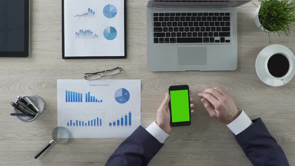 Businessman Scrolling Pages on Green Screen Smartphone in Office, Top View