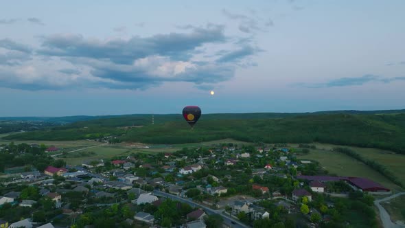 hot air balloon with people during the dusk over a small village wit