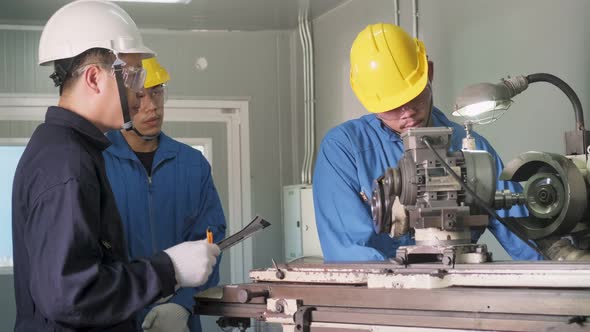 Asian mechanical technicians workers working on a milling and operating machine in factory.