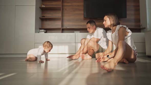 Cute Happy Little Toddler Baby Boy is Crawling to His Parents on a Wooden Floor at Home