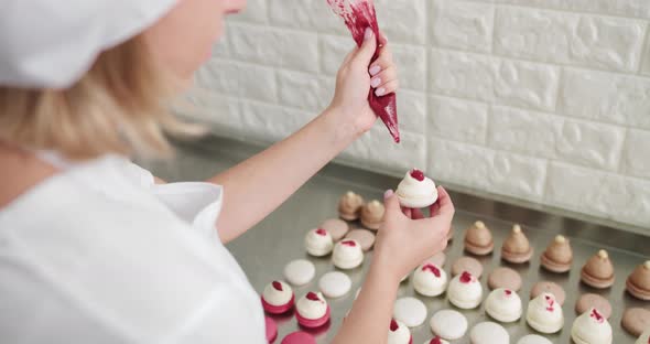 Shot of Hands of Female Pastry Chef Holding White Macaron with Ganache and