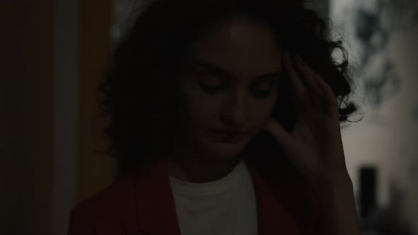 Portrait of Scared Young Woman Standing Outdoors Illuminated with Police Lights and Touching Head