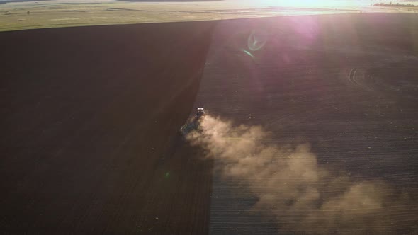 Aerial View Modern Red Tractor on the Agricultural Field on Sunset Time. Tractor Plowing Land and