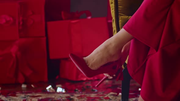 Closeup a Woman in a Red Dress Puts on Red Shoes Sitting on an Armchair in a Hotel Room a Woman is